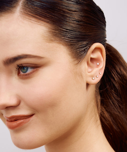 Close-up of a woman's face with a focus on her earrings against a neutral background